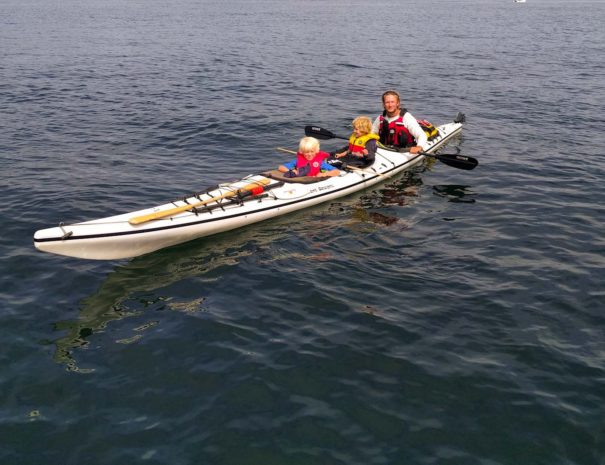 Family, father and kids kayaking together in triple kayak